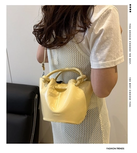 Detail of yellow patent leather bucket bag with knotted handle and adjustable strap