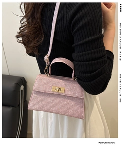 Close-up of pink sequined crossbody bag featuring a golden twist lock and adjustable strap