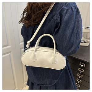 Close-up of white minimalist Boston bag with thick round handles and adjustable shoulder strap