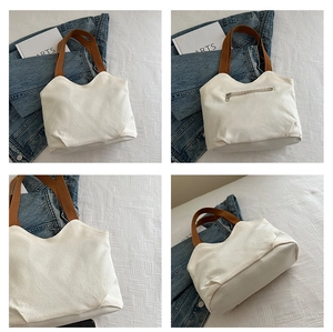 Detail view of white canvas tote bag with brown straps and rear zipper pocket