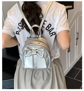 Silver leather mini backpack featuring a large bow knot shown on a model's back