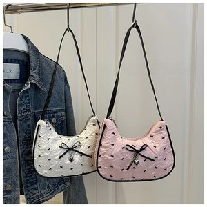 Détail du sac croissant en tissu plissé avec motifs nœuds et pendentif en forme de cœur