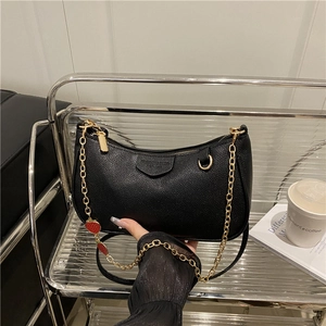 Retro black leather underarm bag with gold chain and strawberry charm on display