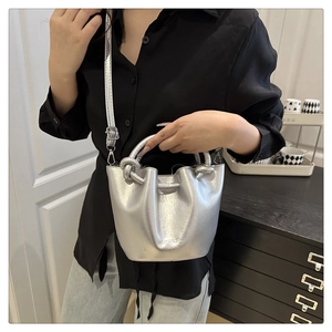 Detail of silver bucket bag featuring knotted handles and SUIZH BAG FASHION logo