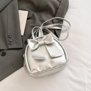 Detailed view of silver mini backpack featuring a large bow and glossy metallic finish