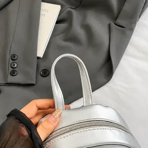 Detailed macro view of the silver metallic backpack handle with smooth zipper closure
