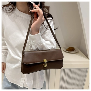 Dettaglio borsa sottobraccio marrone scuro con chiusura dorata su camicia bianca