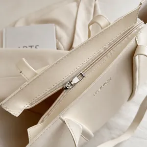 Close-up of the smooth gold-toned zipper and fashion embossed detail on the cream tote bag