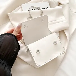 Detalle de los cierres magnéticos plateados y cuero blanco texturizado del bolso mujer