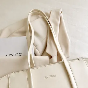 Detail view of reinforced wide shoulder straps on a minimalist cream tote bag