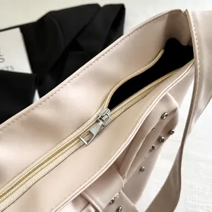 Details des glatten Silber-Reißverschlusses und der Strassnieten auf der weißen Tasche