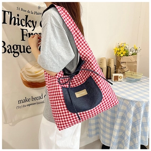 Détail du sac cabas à carreaux rouges avec poche en denim et étiquette de mode centrale