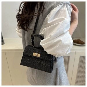 Macro detail of black glitter handbag featuring gold metal lock and stylish top handle