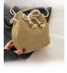Dettaglio della borsa a secchiello intrecciata beige con motivo a spina di pesce e coulisse