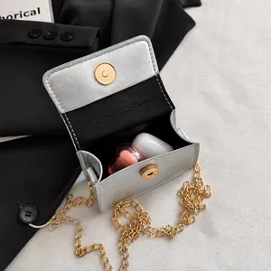 Detail view of mini silver bow crossbody bag showing space for lipstick and earphones