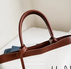 Détail de la poignée en cuir PU et corps en toile blanche sur un sac fourre-tout