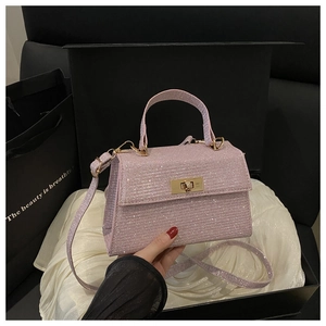 Detailed view of pink glitter Kelly bag with gold metal clasp in a gift box