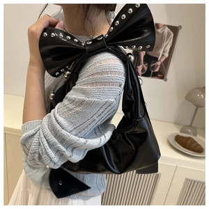 Dettaglio della borsa in pelle nera con maxi fiocco e borchie in metallo argentato