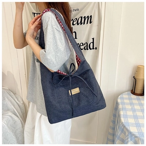 Detail van blauwe denim tas met rood geruite voering en modieus strikje als accent