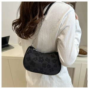 Detail of black floral jacquard underarm bag with silver chain strap on model