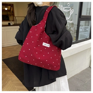Detailweergave van de rode canvas shopper met witte bloemenpatronen en Creative Cat label