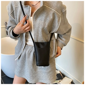 Détail d'un mini sac bandoulière en cuir noir grainé porté avec une tenue décontractée