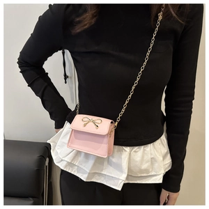 Close-up of mini pink crossbody bag with a delicate golden metal bow detail