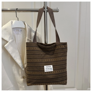 Détail du sac cabas en toile à rayures marron avec texture tissée et écusson blanc