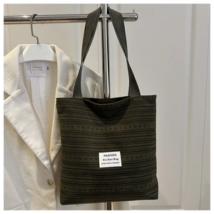 Vue détaillée du sac cabas tissé vert foncé suspendu avec une veste décontractée