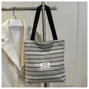Détail du cabas en denim rayé avec étiquette tendance et bandoulière noire robuste