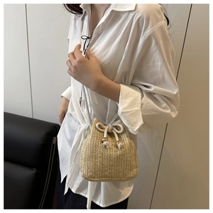 Dettaglio della borsa a secchiello intrecciata beige con coulisse e nappe eleganti