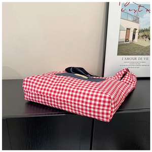 Detailopname van de rood-wit geruite canvas tote bag met geweven riemen op houten tafel