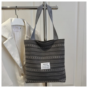 Détail d'un sac cabas en toile rayée avec étiquette carrée en tissu sur surface tissée