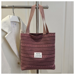 Détail d'un sac cabas en toile à rayures bordeaux suspendu avec une veste blanche