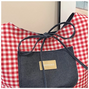 Detailopname van de rood geblokte tas met denim vak en decoratieve strik aan de mond