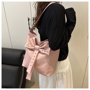 Rosa Schultertasche mit großer Schleife und Silbernieten in minimalistischem Interieur