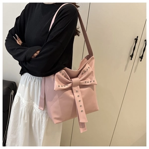 Detail der rosa Schleifen-Tote-Bag mit Metallnieten und breitem Schultergurt am Model