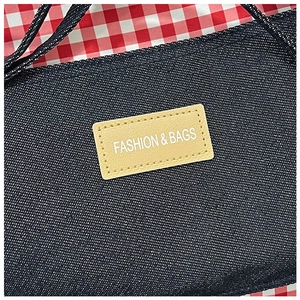 Detail van denim draagtas met gestikt leren label voorzien van fashion bags tekst erop