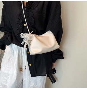 Detail of cream white cloud bag featuring pearl beads and lace bow on smooth PU leather