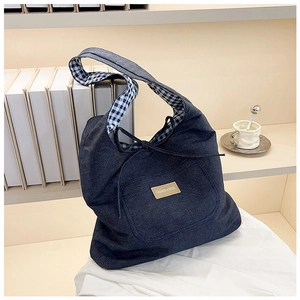 Détail du sac cabas en jean avec doublure à carreaux et écusson en cuir mode sur le devant