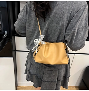 Detail der khakifarbenen Cloud Bag mit Perlen und Spitzenschleife auf glattem Leder