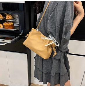 Detail der khakifarbenen Leder-Cloud-Tasche mit Perlen und Spitzenschleife im Haus
