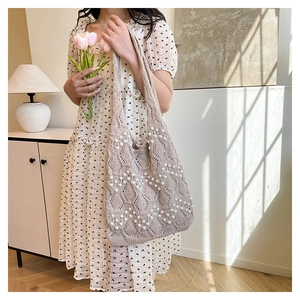 Détail du sac cabas en tricot beige avec crochet évidé et décorations de perles blanches