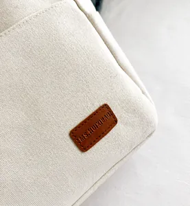 Detalle del bolso de lona con textura gruesa, etiqueta de cuero y costuras precisas