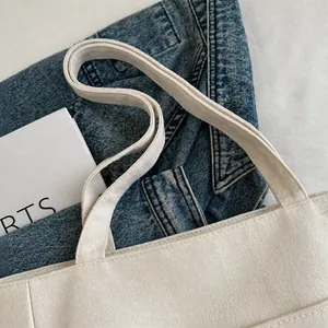 Detalle del asa de lona reforzada en un bolso tote blanco roto con costuras impecables