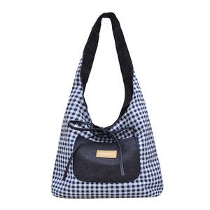 Blauw en wit geruite draagtas met denim zak en leren label op een witte achtergrond
