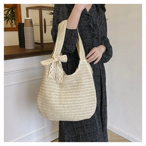 Straw tote bag with lace bow detail shown on shoulder in a cafe setting