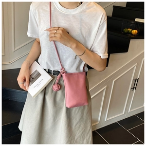 Détail du mini sac bandoulière rose en cuir grainé avec une poignée décorative nouée