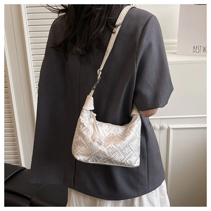Macro detail of white floral jacquard fabric and tassel on women's hobo shoulder bag