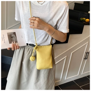 Détail du mini sac bandoulière en cuir jaune avec nœud sphérique unique sur la sangle